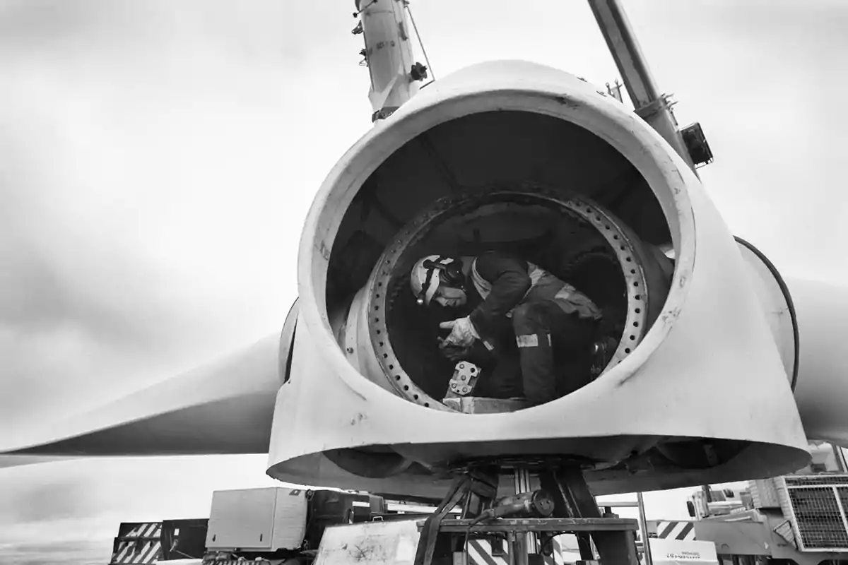 A technician works inside a wind turbine on a cloudy day.