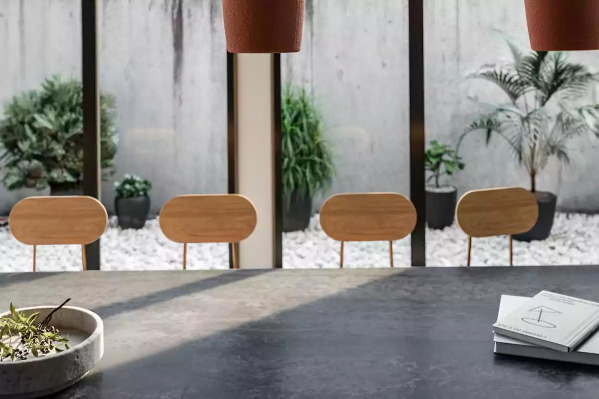 Un comedor moderno con sillas de madera y una mesa de piedra, con vista a un jardín minimalista con plantas en macetas.