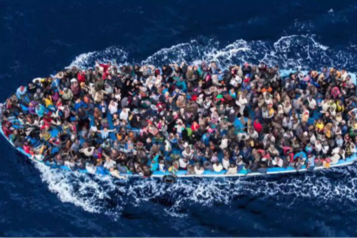 Una embarcación sobrecargada de personas navegando en el mar. Una embarcación sobrecargada de personas navegando en el mar.
