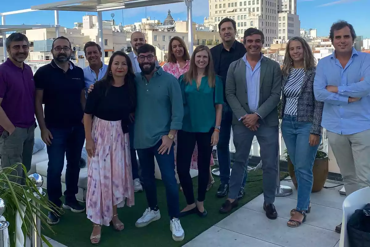 Un grupo de personas posando juntas en una terraza con edificios de fondo.