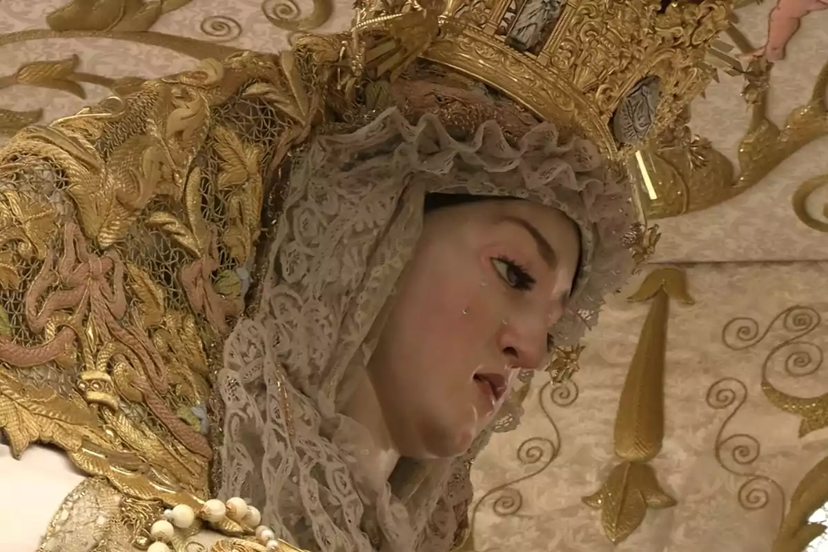 Una imagen de una figura religiosa con un manto dorado y una corona elaborada. Una imagen de una figura religiosa con un manto dorado y una corona elaborada.