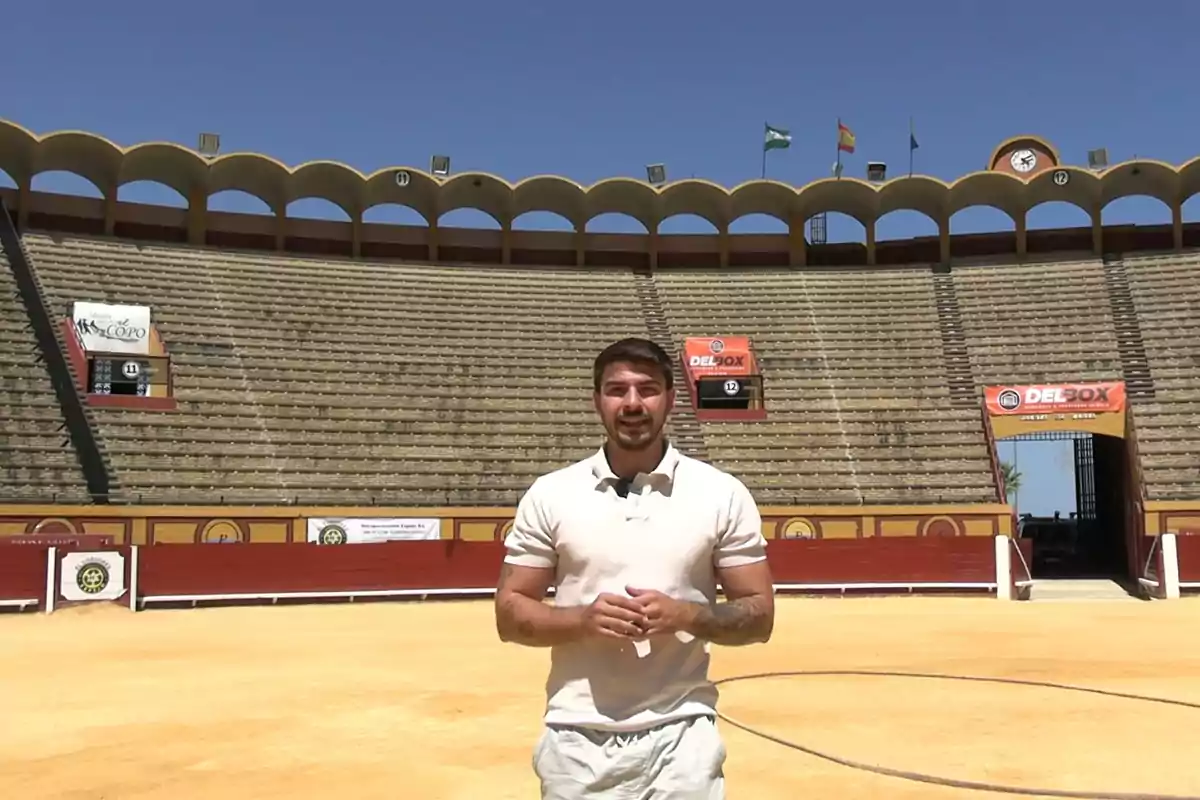 Un hombre de pie en el centro de una plaza de toros vacía bajo un cielo despejado Un hombre de pie en el centro de una plaza de toros vacía bajo un cielo despejado
