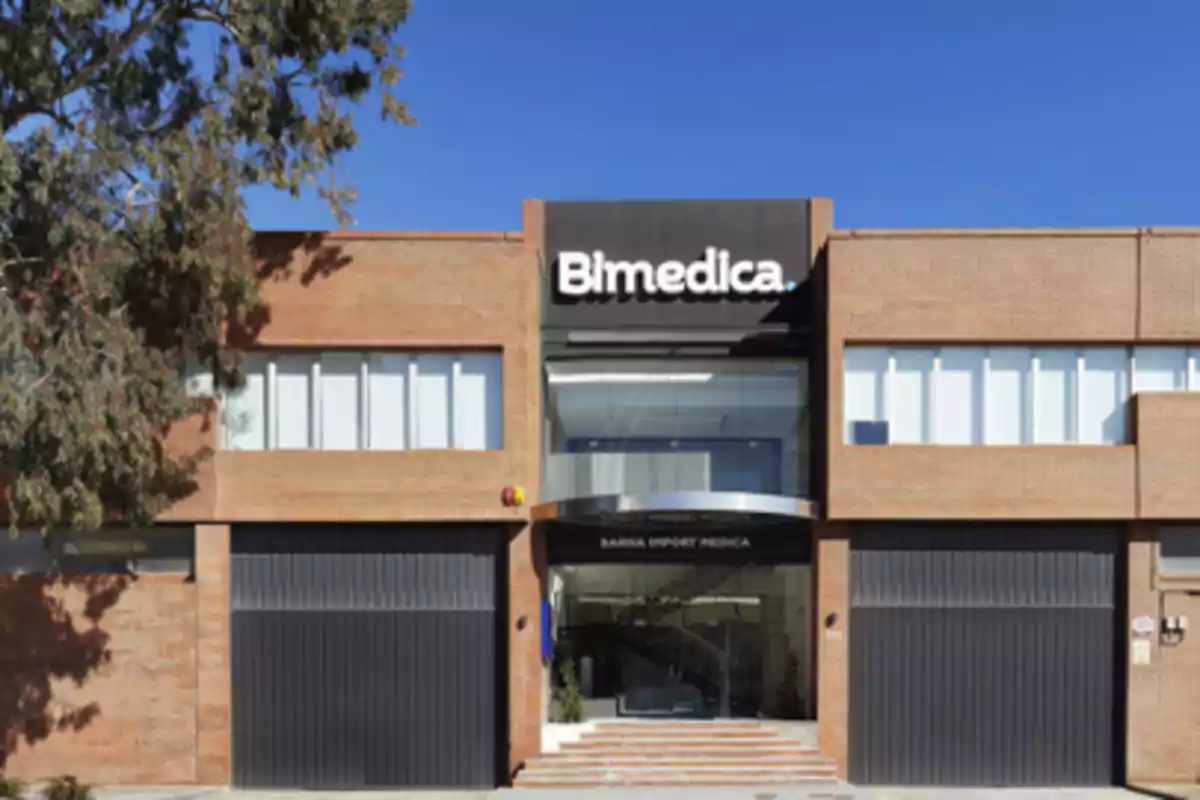 Fachada de un edificio de ladrillo con el letrero Bimedica en la parte superior y un cielo azul de fondo