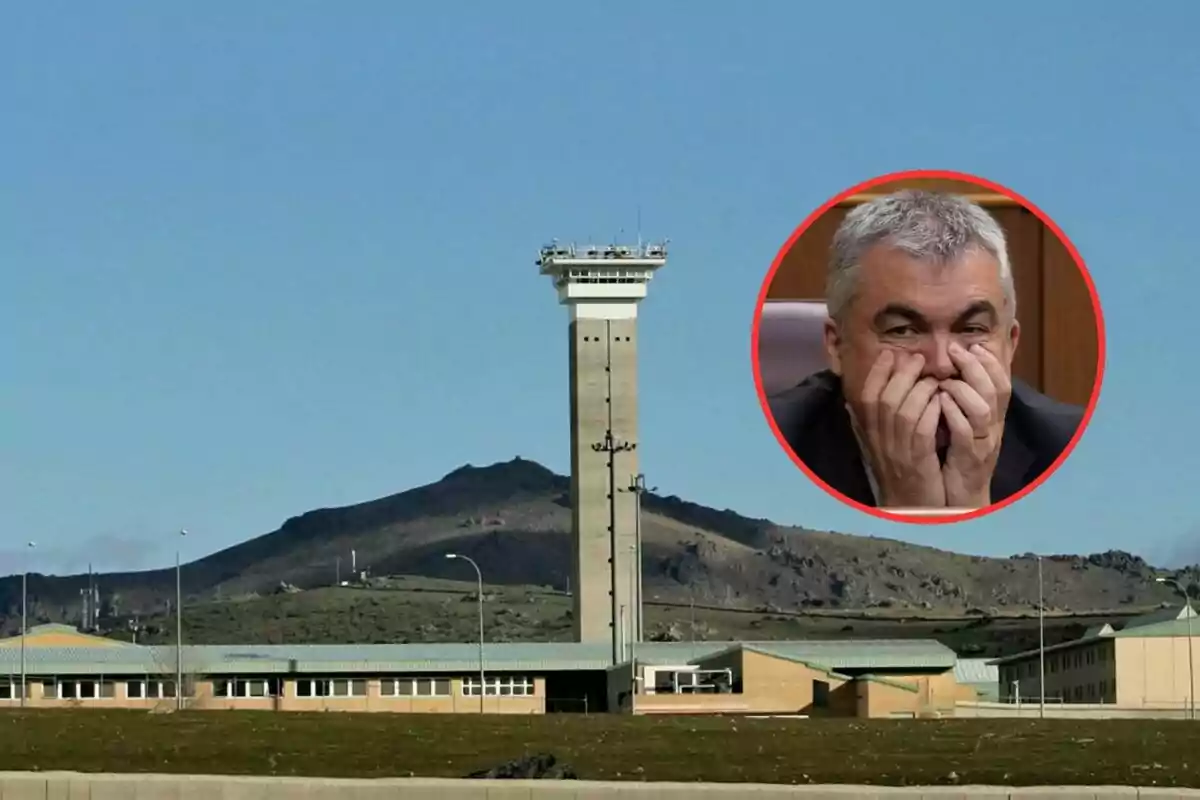 Vista de una prisión con una torre de vigilancia al fondo y un círculo rojo que muestra a un hombre canoso con expresión preocupada cubriéndose la boca con las manos