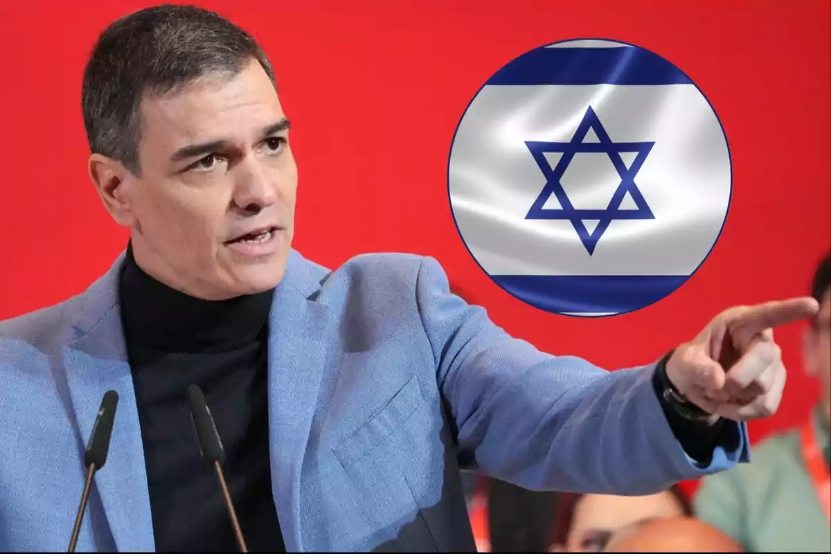 Hombre de cabello corto con chaqueta azul hablando y señalando mientras al fondo aparece un círculo con la bandera de Israel sobre un fondo rojo