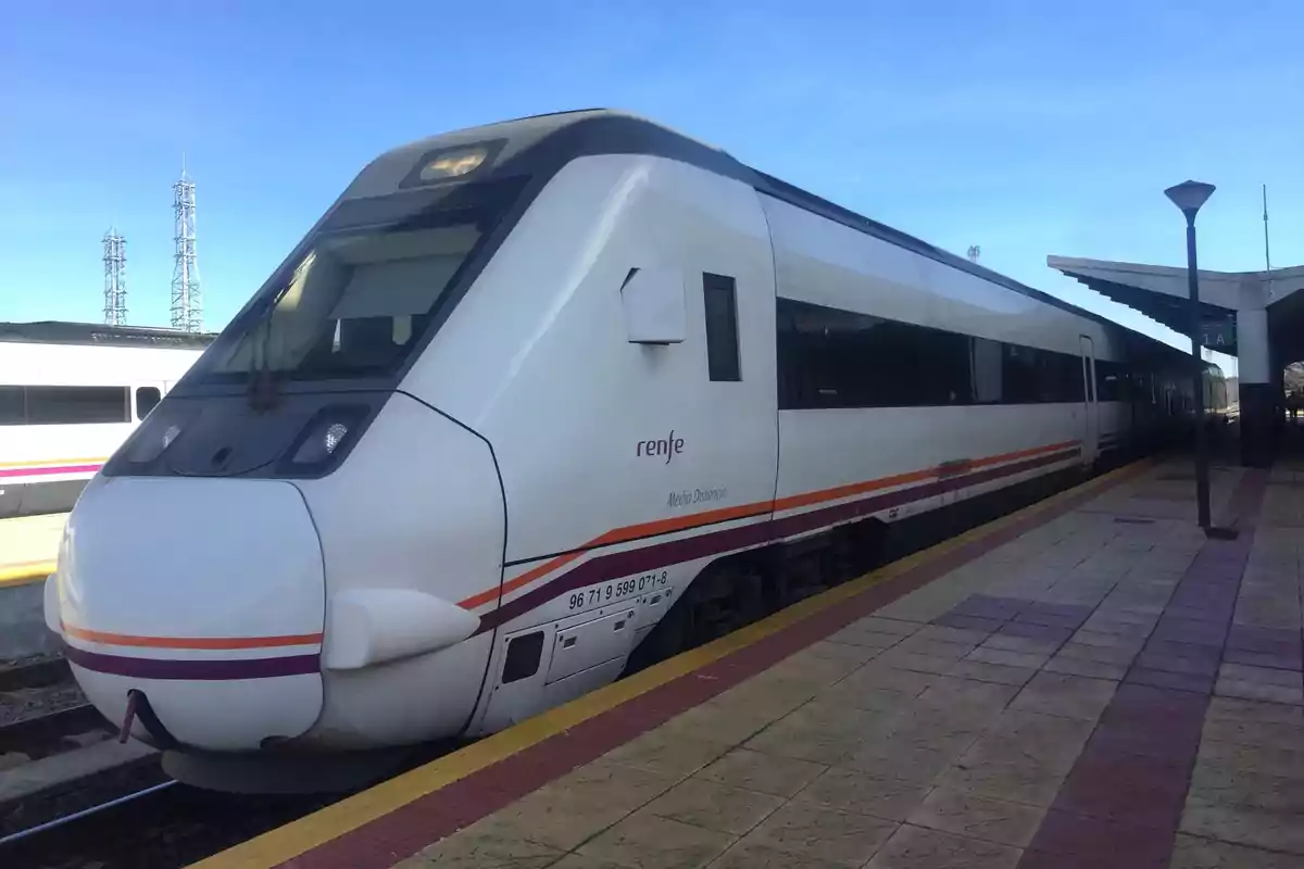 Tren de pasajeros de Renfe detenido en una estación bajo un cielo despejado