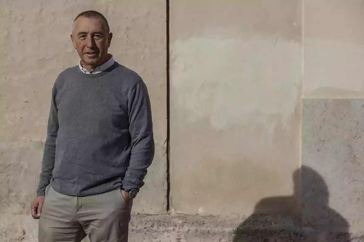 Hombre de pie junto a una pared clara con las manos en los bolsillos y expresión relajada Hombre de pie junto a una pared clara con las manos en los bolsillos y expresión relajada