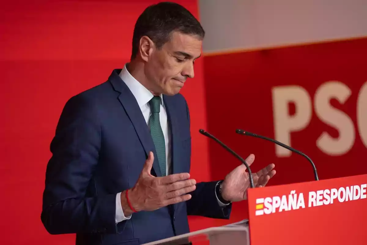 Hombre con traje azul y corbata verde hablando en un atril rojo con el texto España responde y fondo rojo con letras blancas