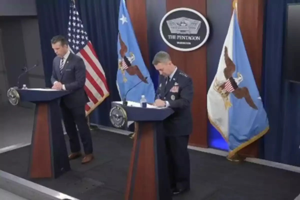 Dos hombres de pie en un podio durante una conferencia de prensa en el Pentágono con banderas oficiales de fondo Dos hombres de pie en un podio durante una conferencia de prensa en el Pentágono con banderas oficiales de fondo