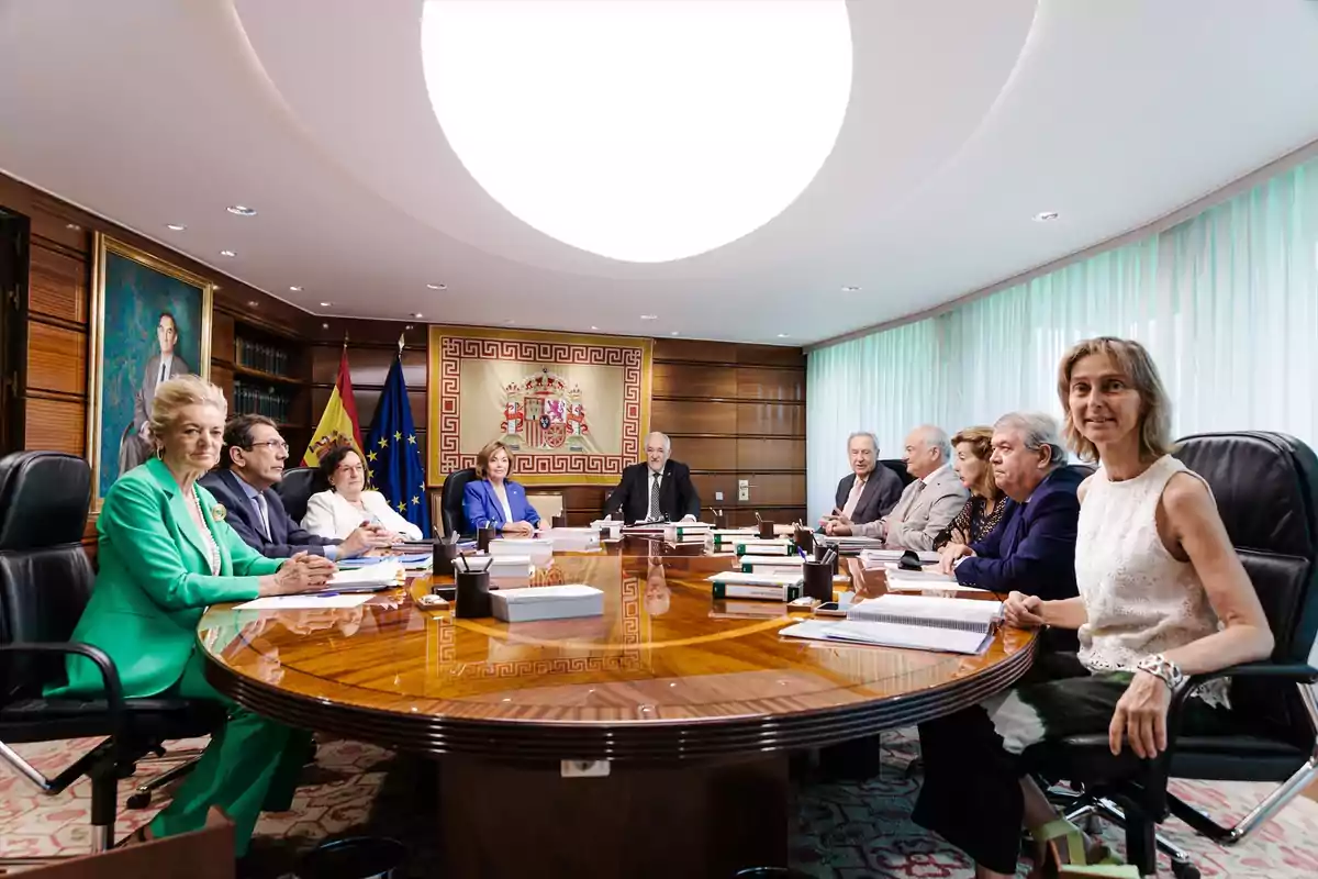 Once personas sentadas alrededor de una mesa ovalada en una sala de reuniones elegante con banderas y un escudo oficial al fondo Once personas sentadas alrededor de una mesa ovalada en una sala de reuniones elegante con banderas y un escudo oficial al fondo