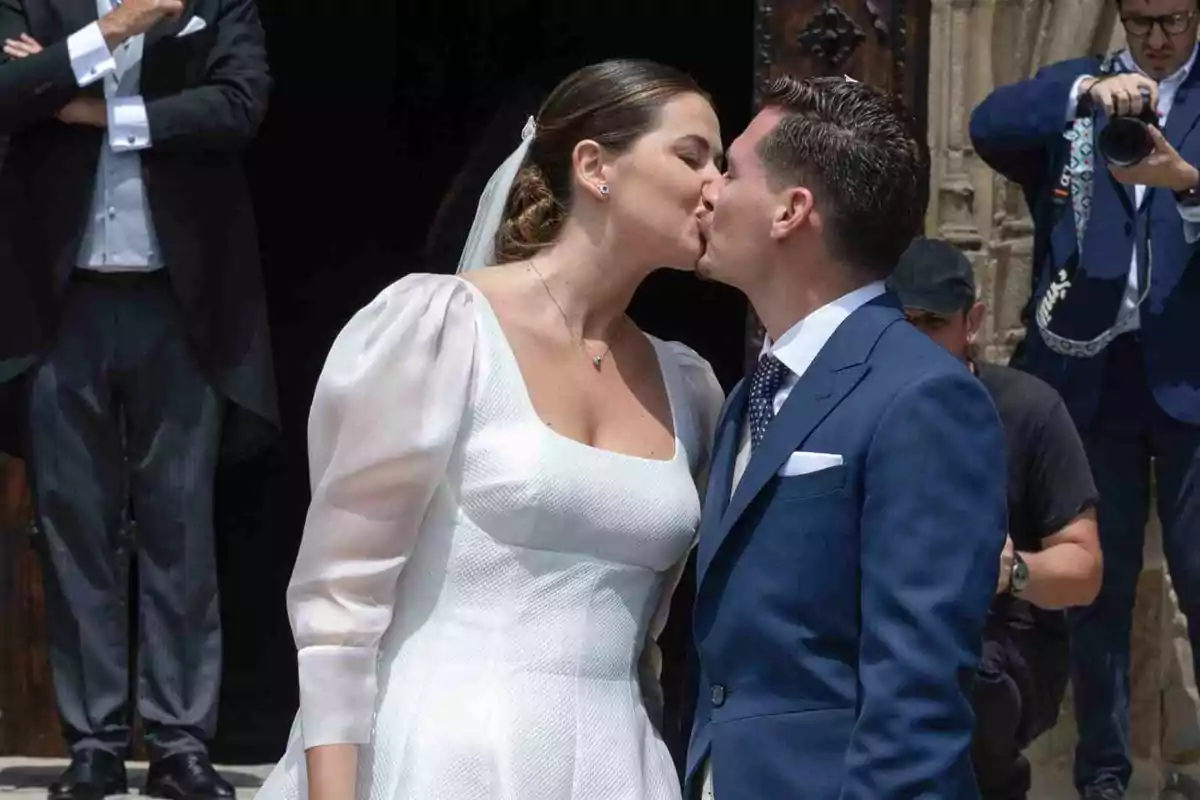 Chema Esteban y Lorena Elorriaga recién casados besándose frente a la iglesia mientras un fotógrafo captura el momento Chema Esteban y Lorena Elorriaga recién casados besándose frente a la iglesia mientras un fotógrafo captura el momento