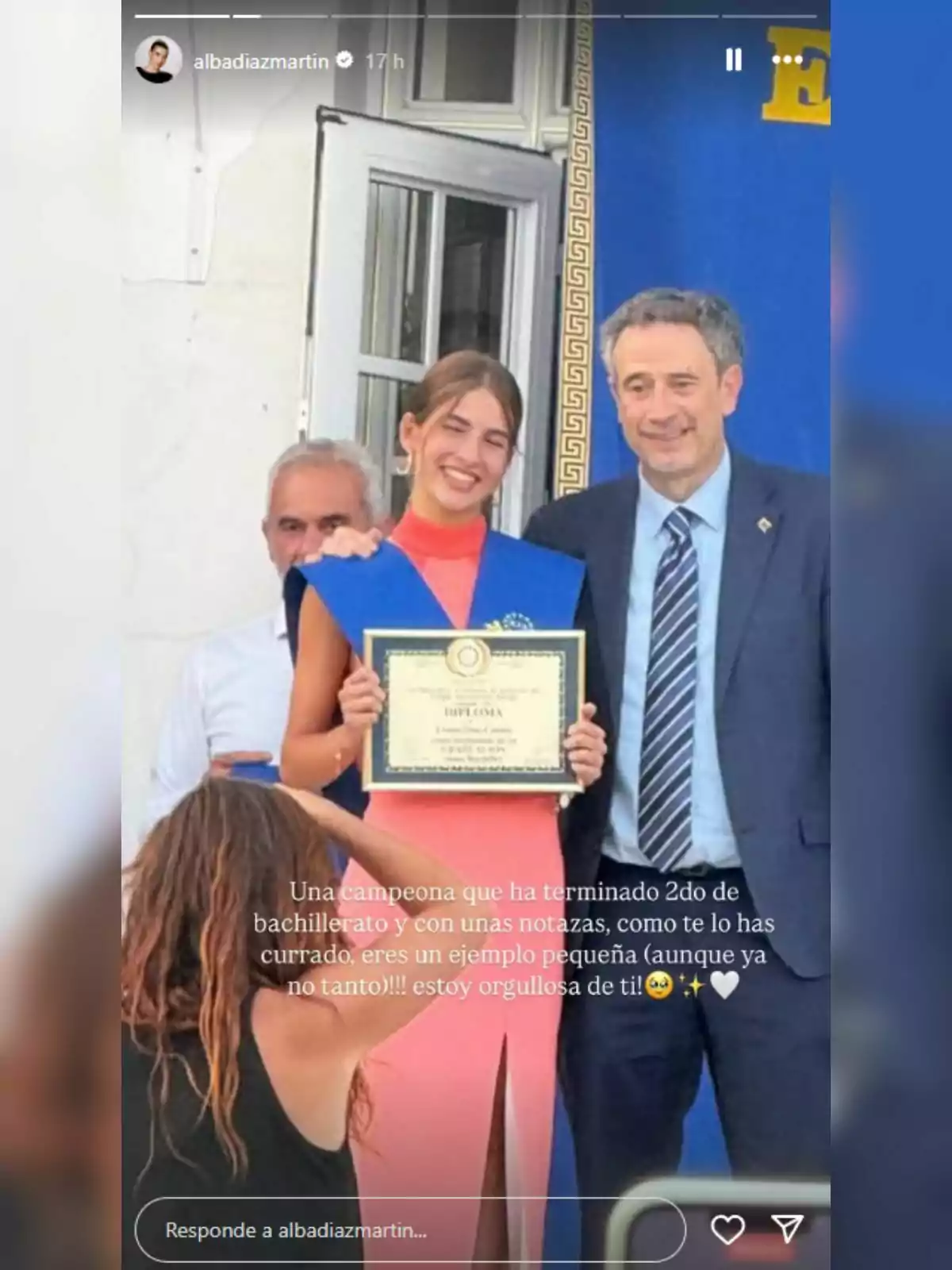 Joven sonriente con banda azul y diploma en la mano posando junto a un hombre con traje durante una ceremonia de graduación. Joven sonriente con banda azul y diploma en la mano posando junto a un hombre con traje durante una ceremonia de graduación.