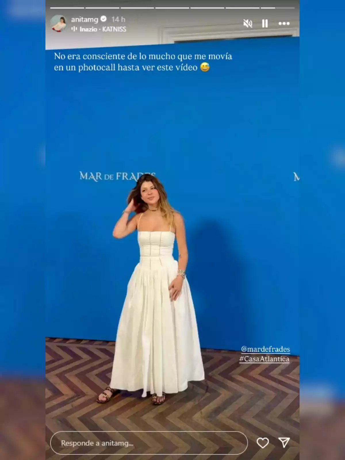 Anita Matamoros vestida con un vestido blanco posando frente a un fondo azul con el texto 'Mar de Frades' y piso de madera en zigzag. Anita Matamoros vestida con un vestido blanco posando frente a un fondo azul con el texto 'Mar de Frades' y piso de madera en zigzag.