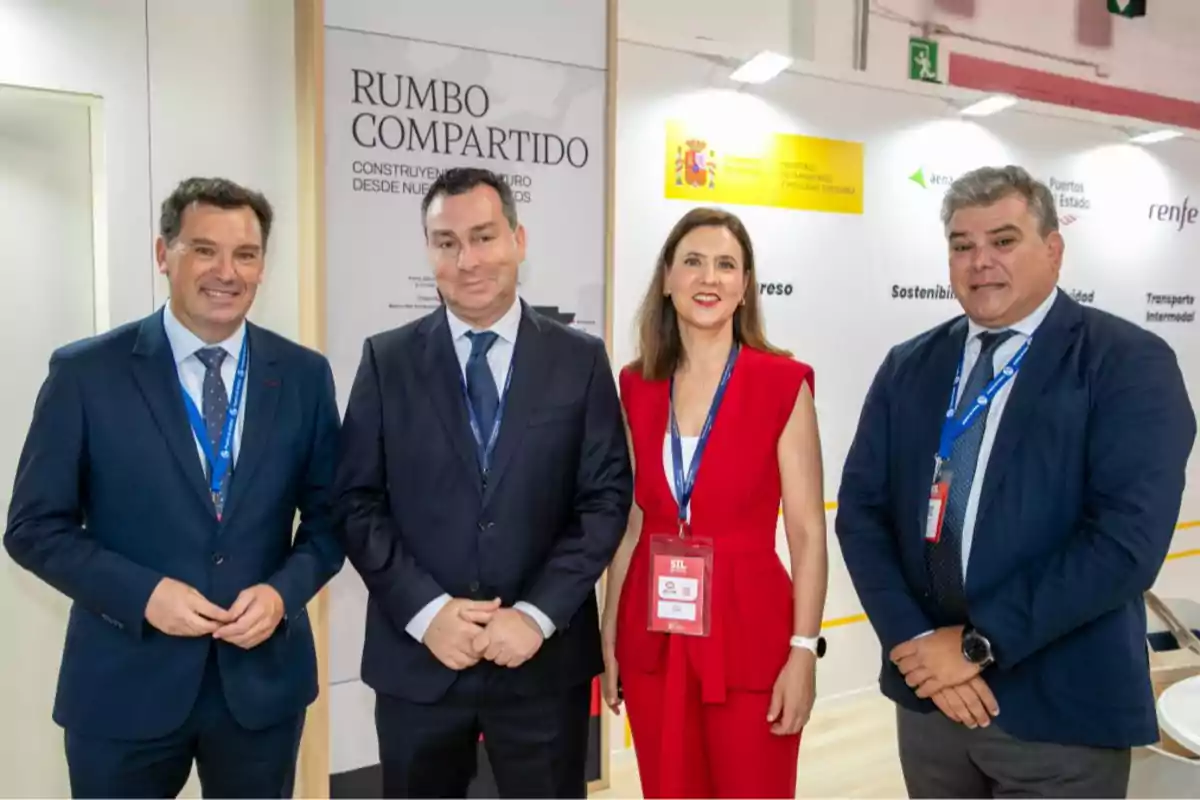Cuatro personas vestidas de manera formal posan sonrientes en un evento profesional frente a un fondo con logotipos institucionales y un cartel que dice Rumbo Compartido.