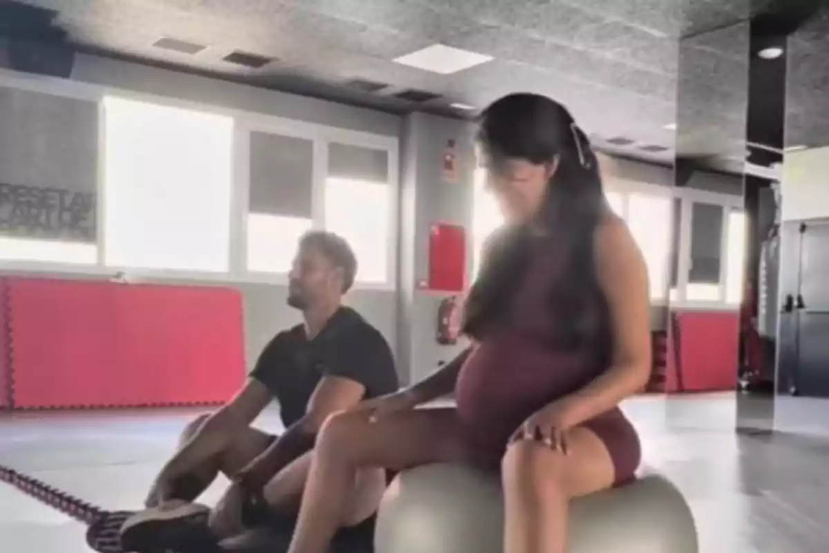 Isa Pantoja embarazada sentada sobre una pelota de ejercicio junto a Asraf Beno en un gimnasio iluminado Isa Pantoja embarazada sentada sobre una pelota de ejercicio junto a Asraf Beno en un gimnasio iluminado