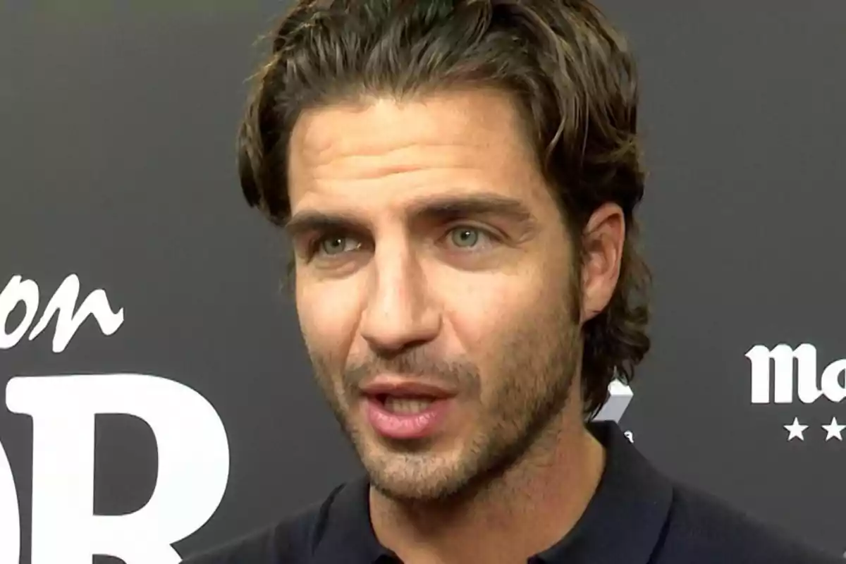 Maxi Iglesias de cabello castaño y ojos claros hablando frente a un fondo oscuro con letras blancas Maxi Iglesias de cabello castaño y ojos claros hablando frente a un fondo oscuro con letras blancas