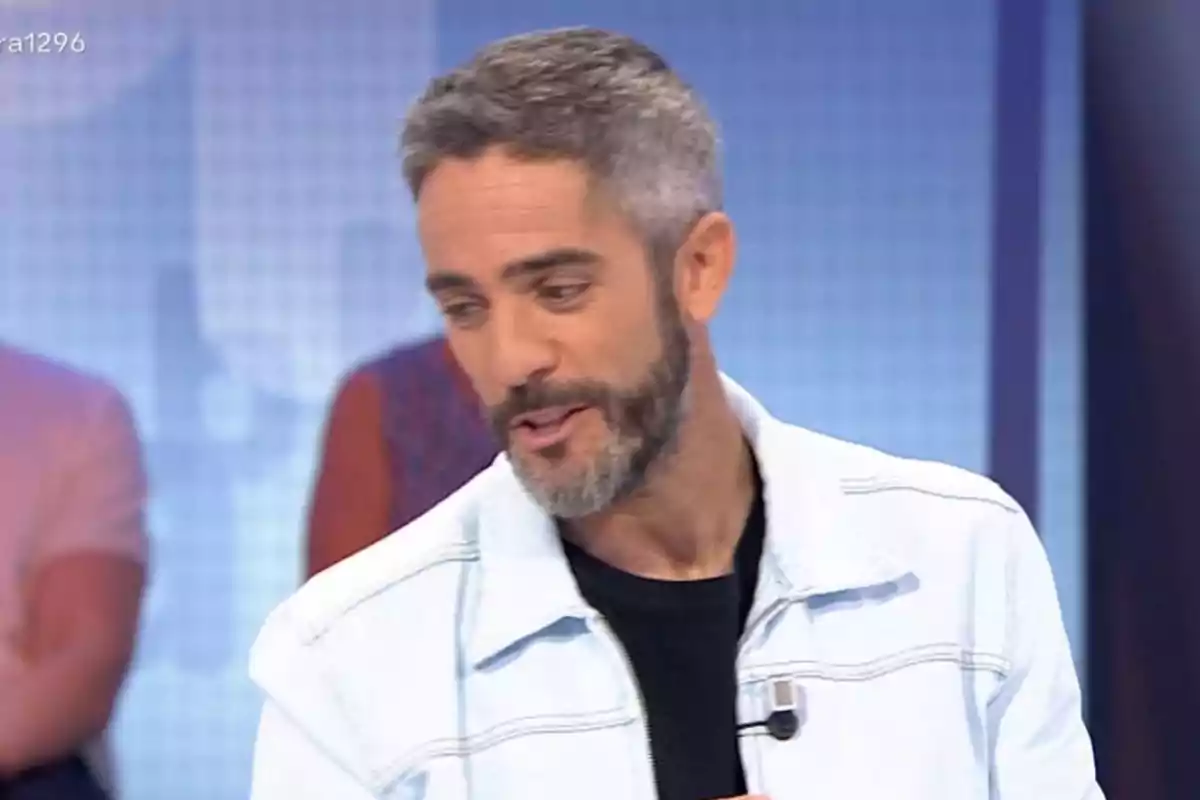 Roberto Leal de cabello corto y barba con chaqueta clara y camiseta oscura en un set de televisión Roberto Leal de cabello corto y barba con chaqueta clara y camiseta oscura en un set de televisión