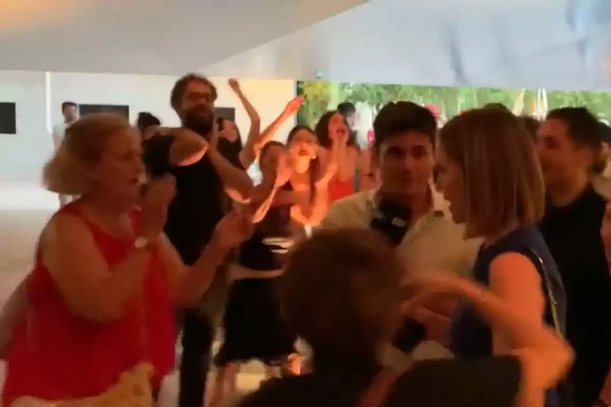 Un grupo de personas discute y gesticula de manera acalorada en un espacio interior iluminado Un grupo de personas discute y gesticula de manera acalorada en un espacio interior iluminado