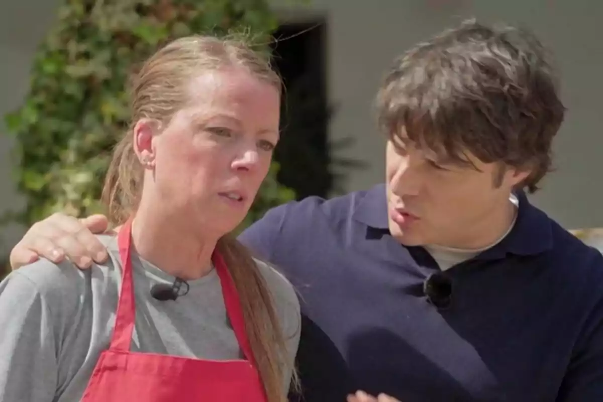 Una concursante de 'MasterChef' con delantal rojo y expresión seria es consolada por Jordi Cruz, que le pone la mano en el hombro mientras conversan al aire libre. Una concursante de 'MasterChef' con delantal rojo y expresión seria es consolada por Jordi Cruz, que le pone la mano en el hombro mientras conversan al aire libre.