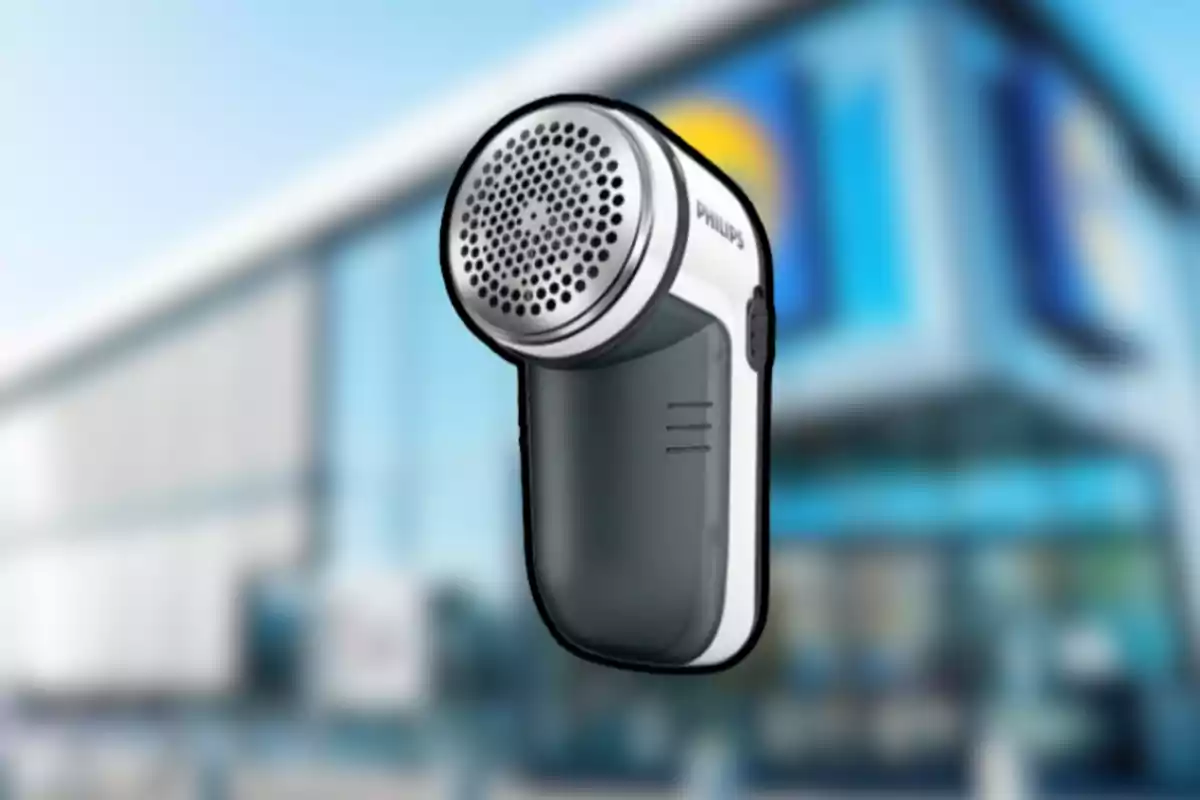 Dispositivo quitapelusas eléctrico de la marca Philips con fondo de edificio desenfocado Dispositivo quitapelusas eléctrico de la marca Philips con fondo de edificio desenfocado