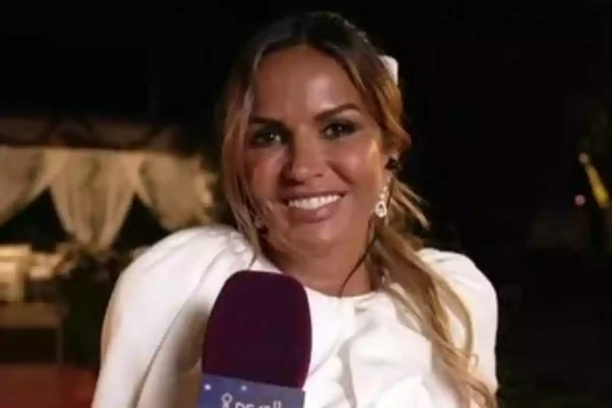 Marta López sonriente con micrófono de De Viernes en la mano vestida de blanco en un evento nocturno al aire libre Marta López sonriente con micrófono de De Viernes en la mano vestida de blanco en un evento nocturno al aire libre