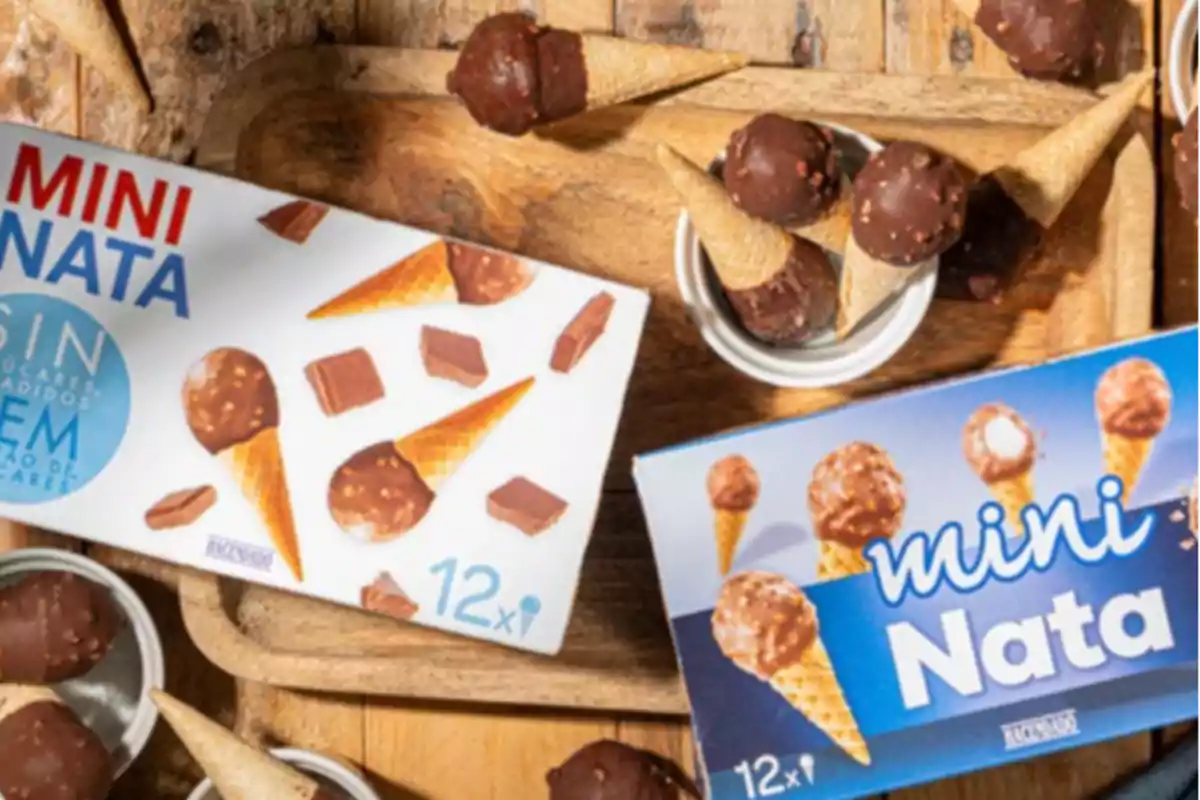 Cajas de helados mini nata junto a conos pequeños cubiertos de chocolate sobre una bandeja de madera Cajas de helados mini nata junto a conos pequeños cubiertos de chocolate sobre una bandeja de madera