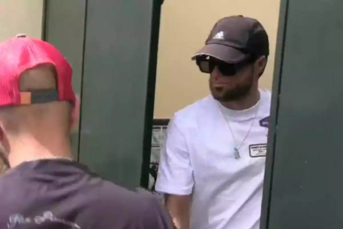 Montoya con gorra, gafass de sol y camiseta casual está cerca de una puerta verde. Montoya con gorra, gafass de sol y camiseta casual está cerca de una puerta verde.