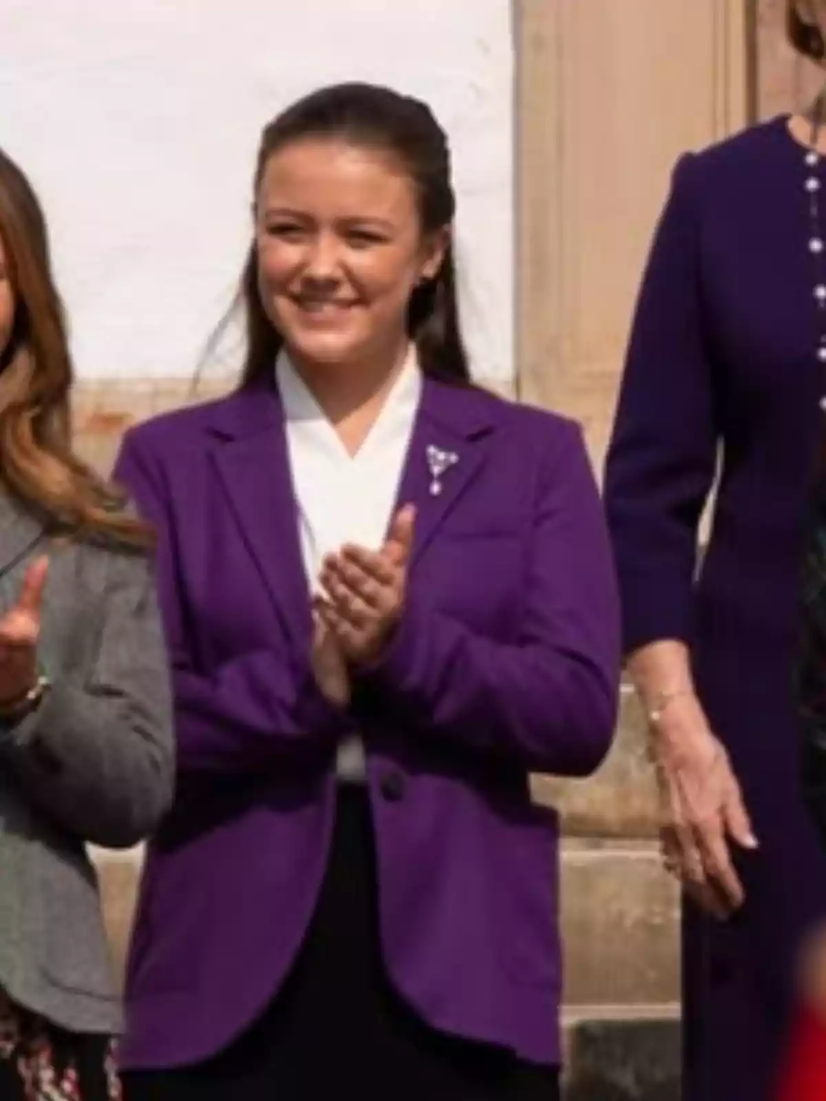 Smiling young man in a purple jacket standing and clapping next to other people Smiling young man in a purple jacket standing and clapping next to other people