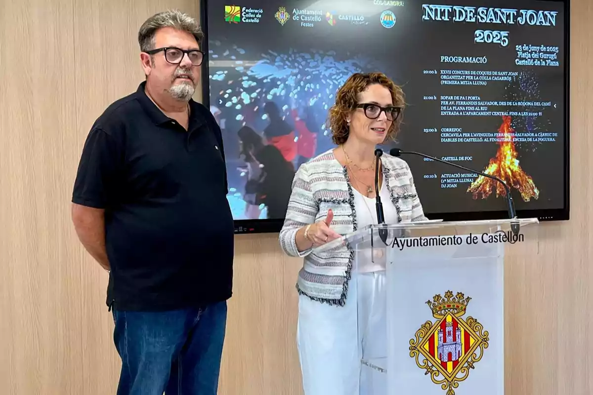 Dos personas presentan un evento en una sala de prensa del Ayuntamiento de Castellón, con un cartel de la Nit de Sant Joan 2025 proyectado en una pantalla al fondo.