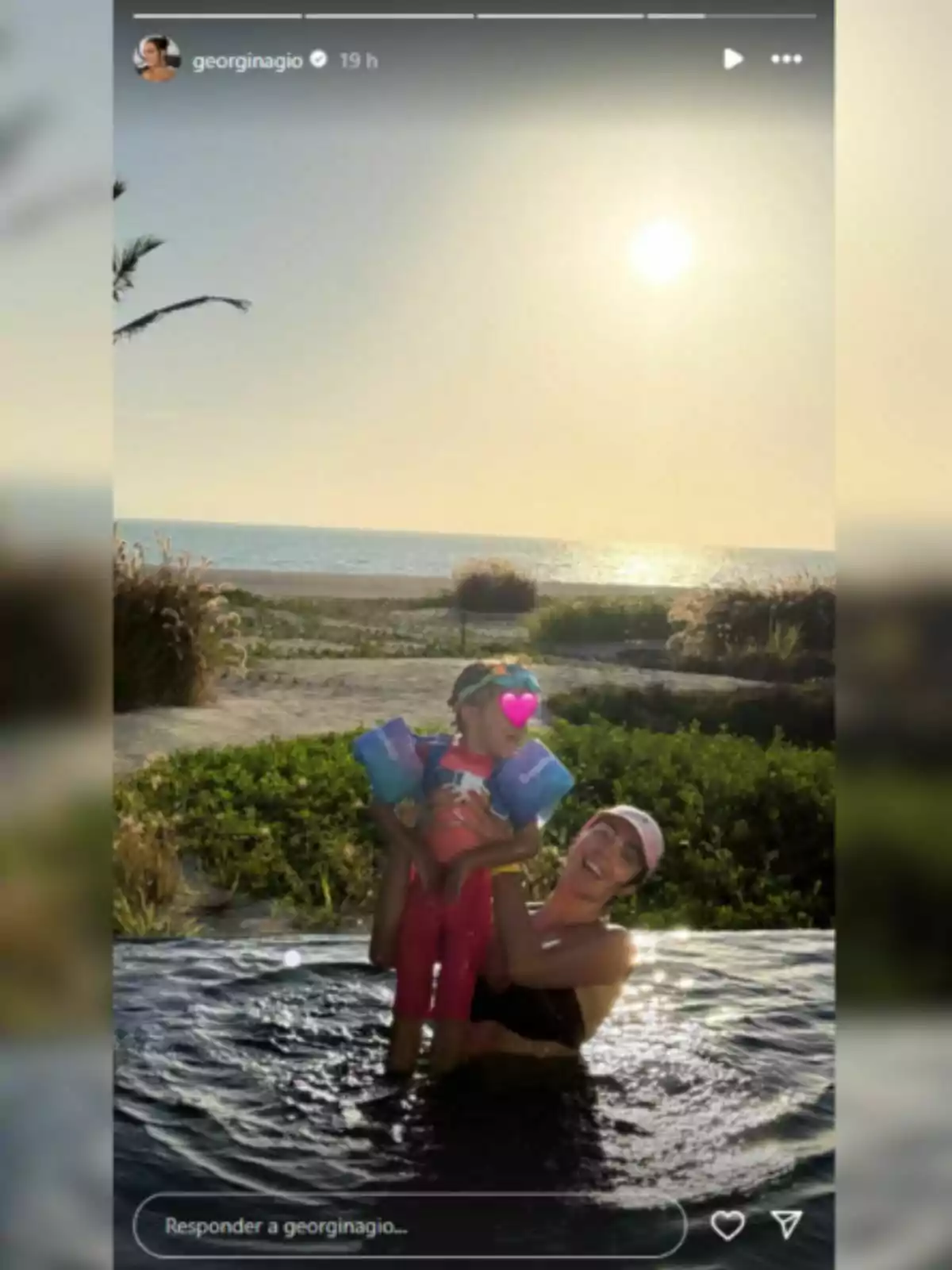 Georgina Rodríguez is in a pool holding a little girl with floaties as they enjoy a sunset by the sea.