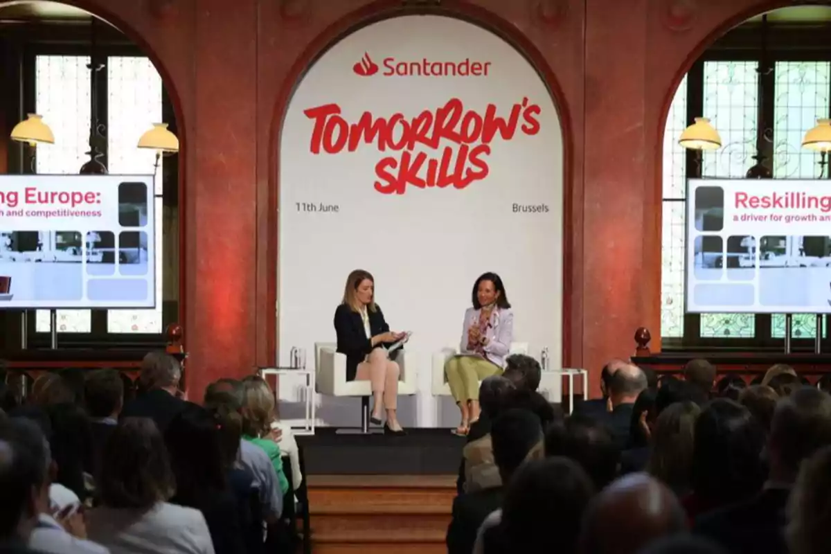 Dos mujeres sentadas en un escenario conversan frente a una audiencia en un evento de Santander titulado Tomorrow's Skills en Bruselas Dos mujeres sentadas en un escenario conversan frente a una audiencia en un evento de Santander titulado Tomorrow's Skills en Bruselas
