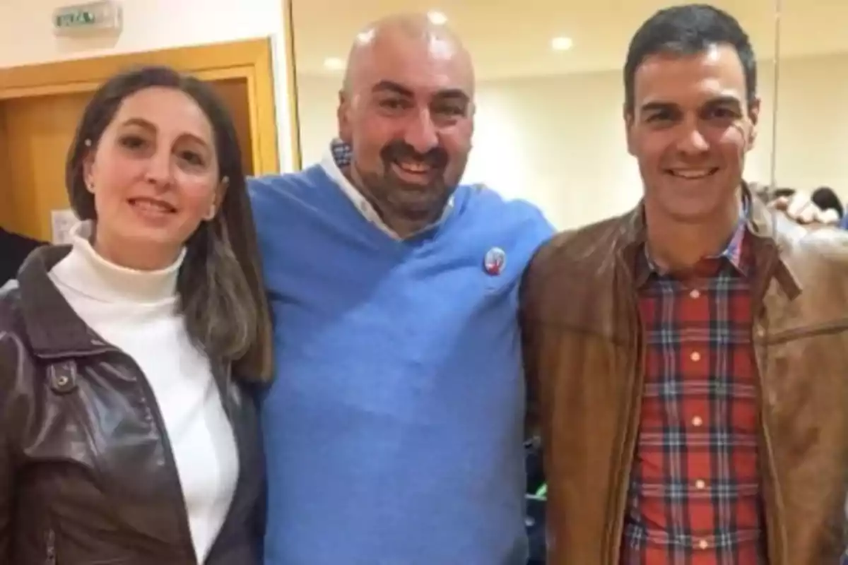 Tres personas posan sonrientes para una foto en un interior, una mujer con chaqueta de cuero marrón y suéter blanco, un hombre calvo con suéter azul y otro hombre con chaqueta marrón y camisa de cuadros rojos. Tres personas posan sonrientes para una foto en un interior, una mujer con chaqueta de cuero marrón y suéter blanco, un hombre calvo con suéter azul y otro hombre con chaqueta marrón y camisa de cuadros rojos.