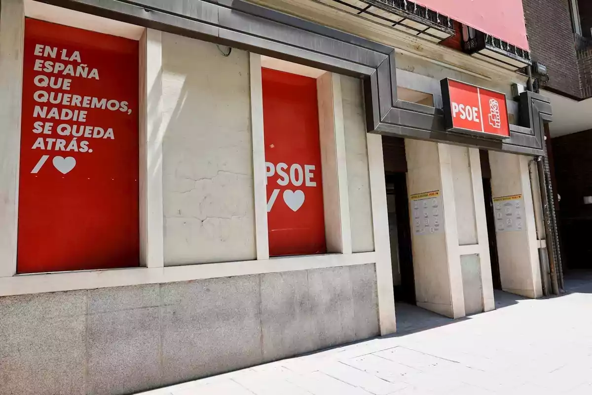 Fachada de una sede del PSOE con carteles rojos y mensajes sobre inclusión social en las ventanas Fachada de una sede del PSOE con carteles rojos y mensajes sobre inclusión social en las ventanas