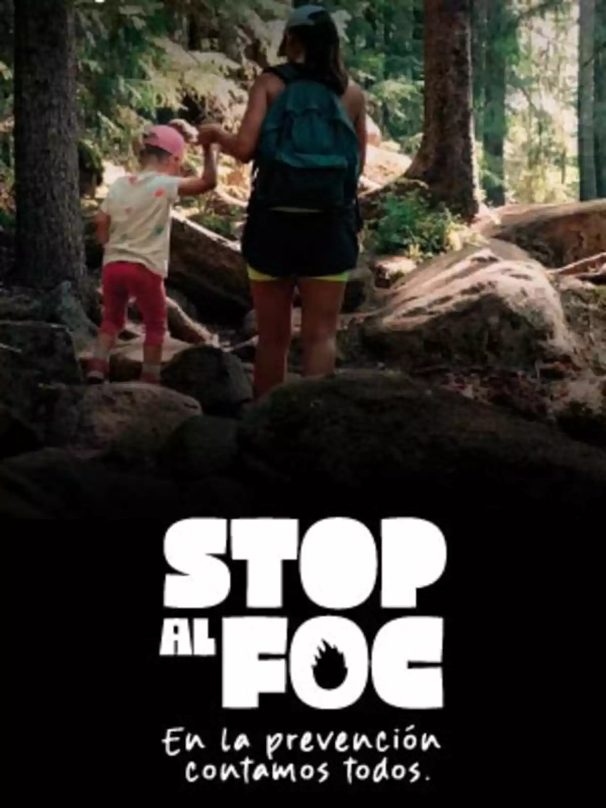 Una mujer y una niña caminan juntas por un sendero en el bosque y en la parte inferior aparece el mensaje Stop al Foc En la prevención contamos todos Una mujer y una niña caminan juntas por un sendero en el bosque y en la parte inferior aparece el mensaje Stop al Foc En la prevención contamos todos