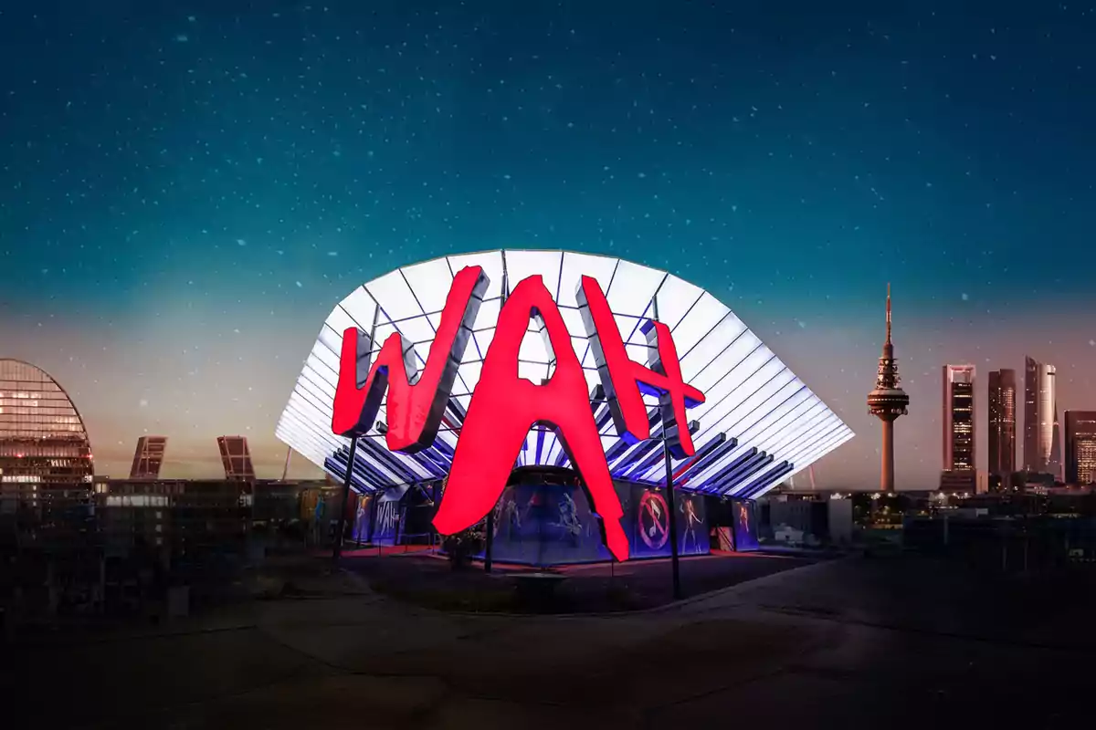 Edificio moderno iluminado con un gran letrero rojo que dice WAH y un cielo estrellado al fondo junto a rascacielos y una torre de telecomunicaciones Edificio moderno iluminado con un gran letrero rojo que dice WAH y un cielo estrellado al fondo junto a rascacielos y una torre de telecomunicaciones