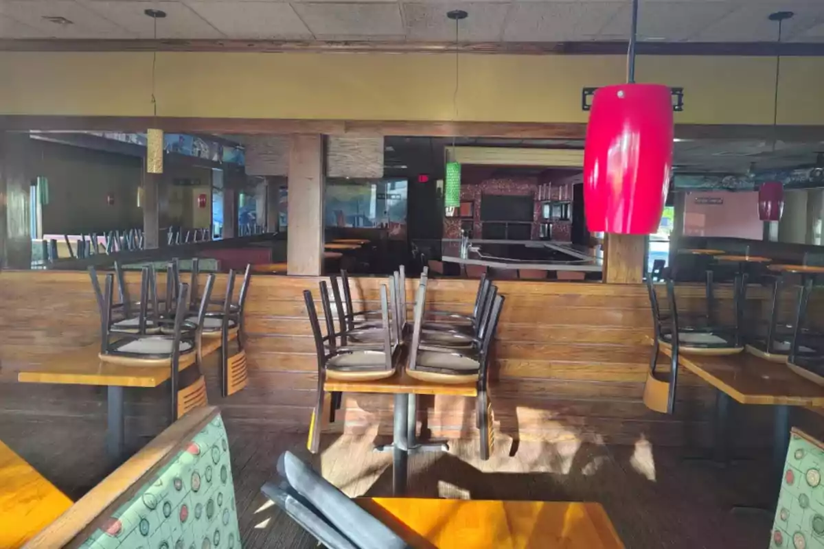 Interior of an empty restaurant with chairs stacked on the tables and red hanging lamps Interior of an empty restaurant with chairs stacked on the tables and red hanging lamps