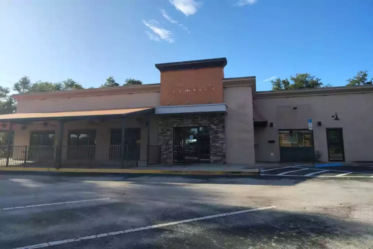 Facade of an empty commercial building with parking in front and clear sky Facade of an empty commercial building with parking in front and clear sky
