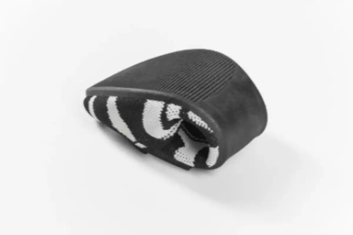 Zapato deportivo negro y blanco doblado sobre una superficie blanca Zapato deportivo negro y blanco doblado sobre una superficie blanca
