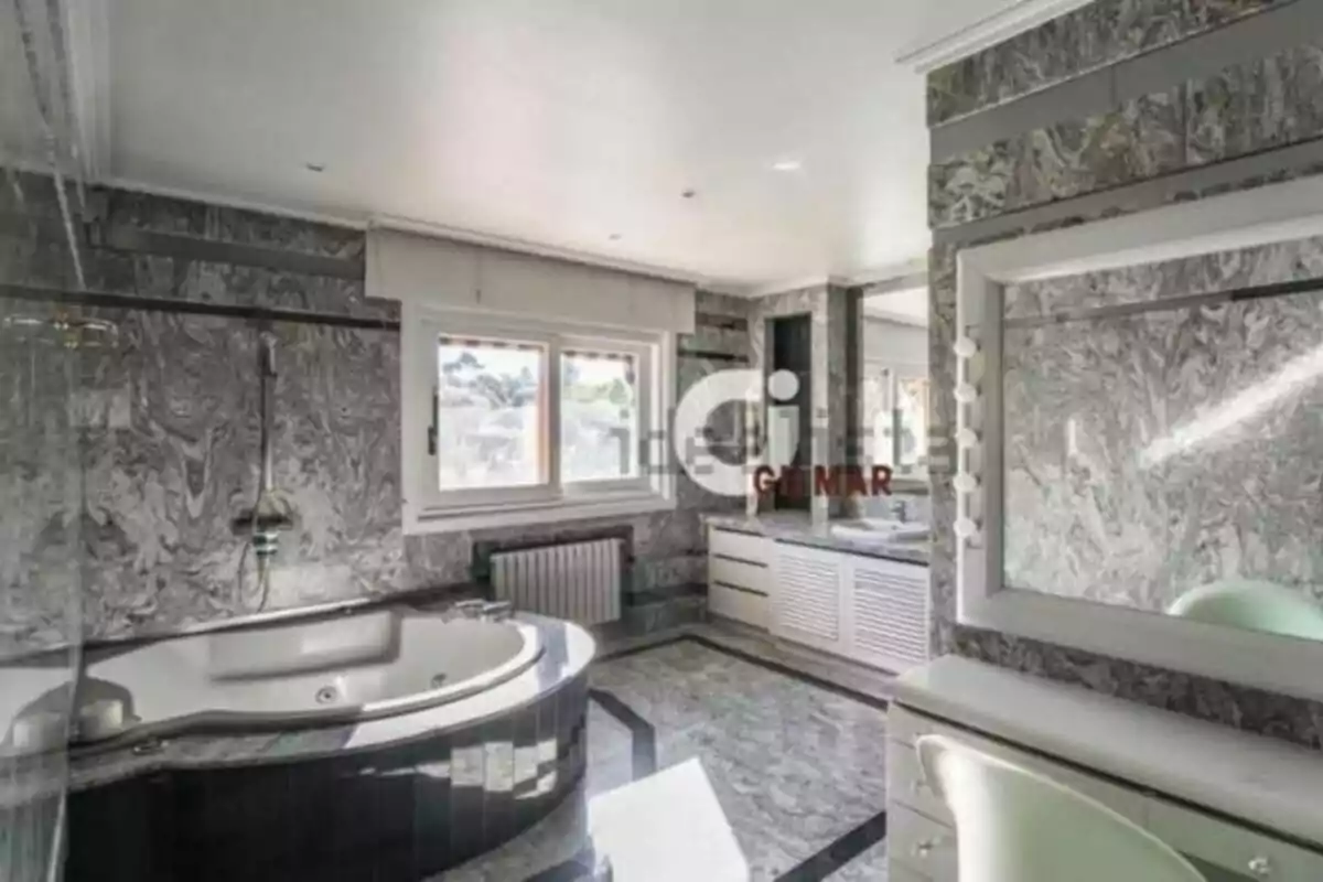 Spacious and elegant bathroom with jacuzzi, gray marble walls and floor, large window, and vanity with illuminated mirror. Spacious and elegant bathroom with jacuzzi, gray marble walls and floor, large window, and vanity with illuminated mirror.