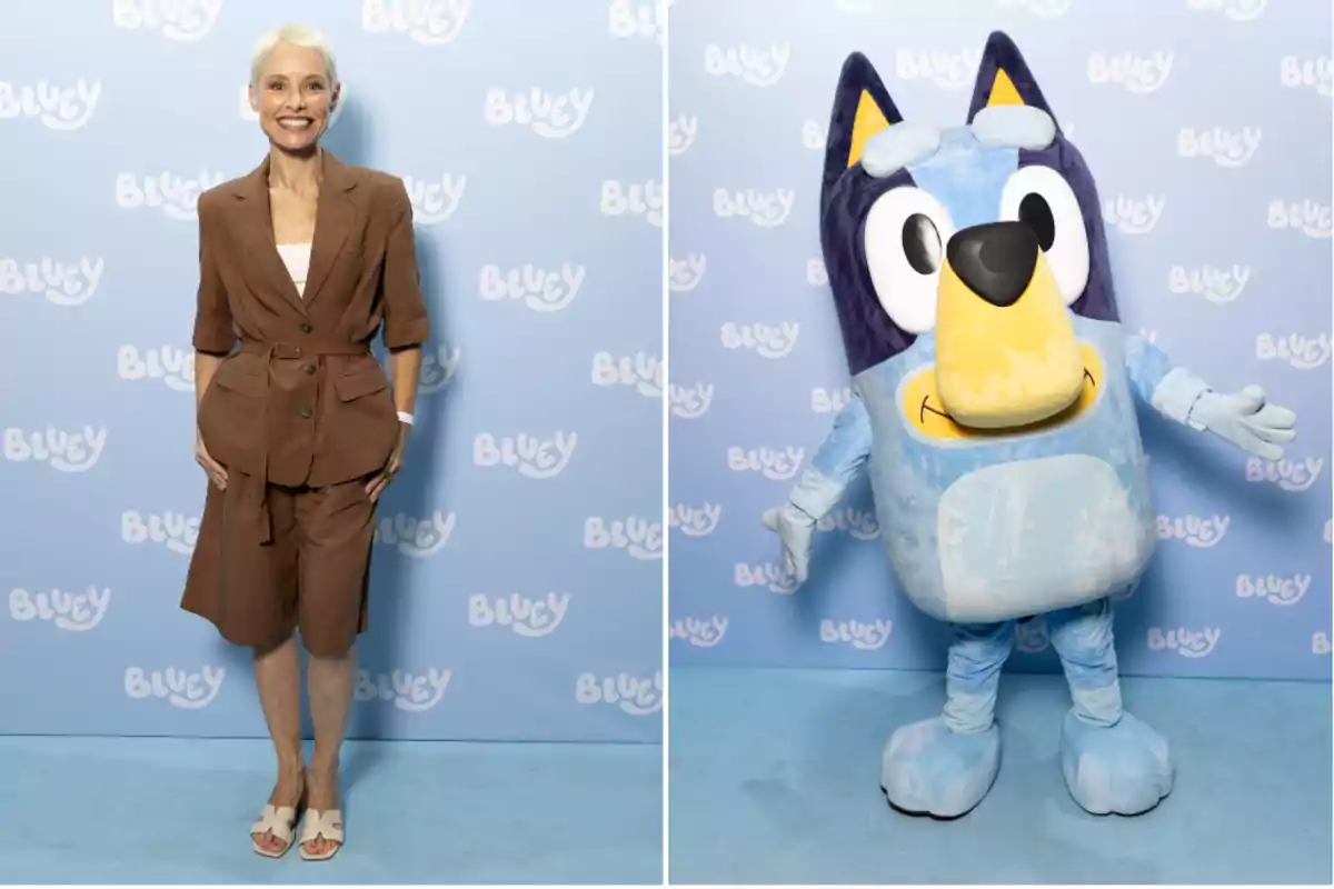 Una mujer sonriente con cabello corto y rubio viste un conjunto marrón claro y sandalias blancas posando frente a un fondo azul con el logo de Bluey mientras en la otra mitad de la imagen aparece una botarga del personaje Bluey con los brazos abiertos sobre el mismo fondo
