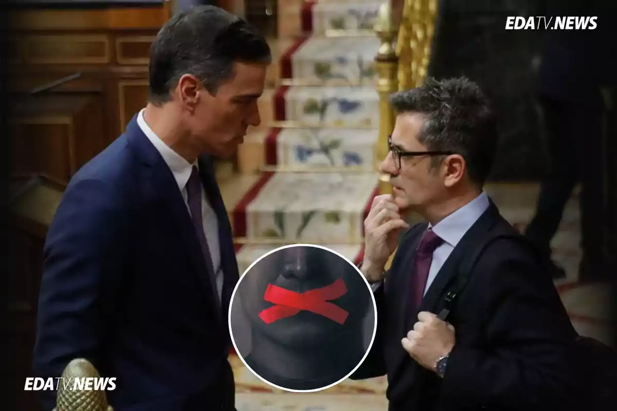 Dos hombres de traje conversan en un entorno formal con una escalera alfombrada al fondo y un círculo superpuesto que muestra una boca tapada con cinta roja en forma de cruz