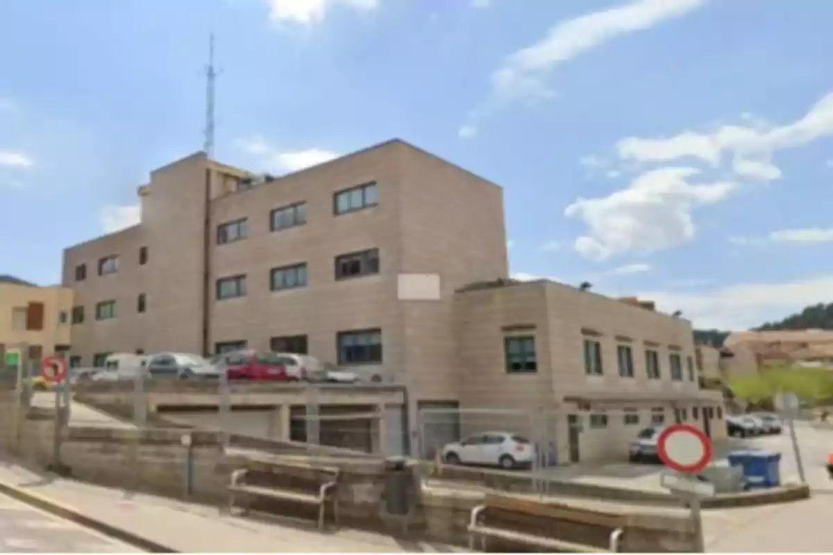 Edificio moderno de varios pisos con ventanas rectangulares y coches aparcados alrededor en un día soleado Edificio moderno de varios pisos con ventanas rectangulares y coches aparcados alrededor en un día soleado