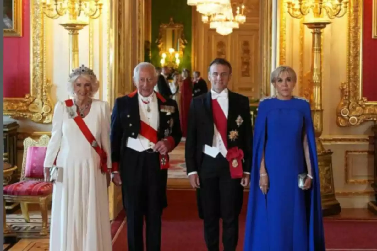 Four elegantly dressed people pose in a luxurious room decorated with golden details and chandeliers.