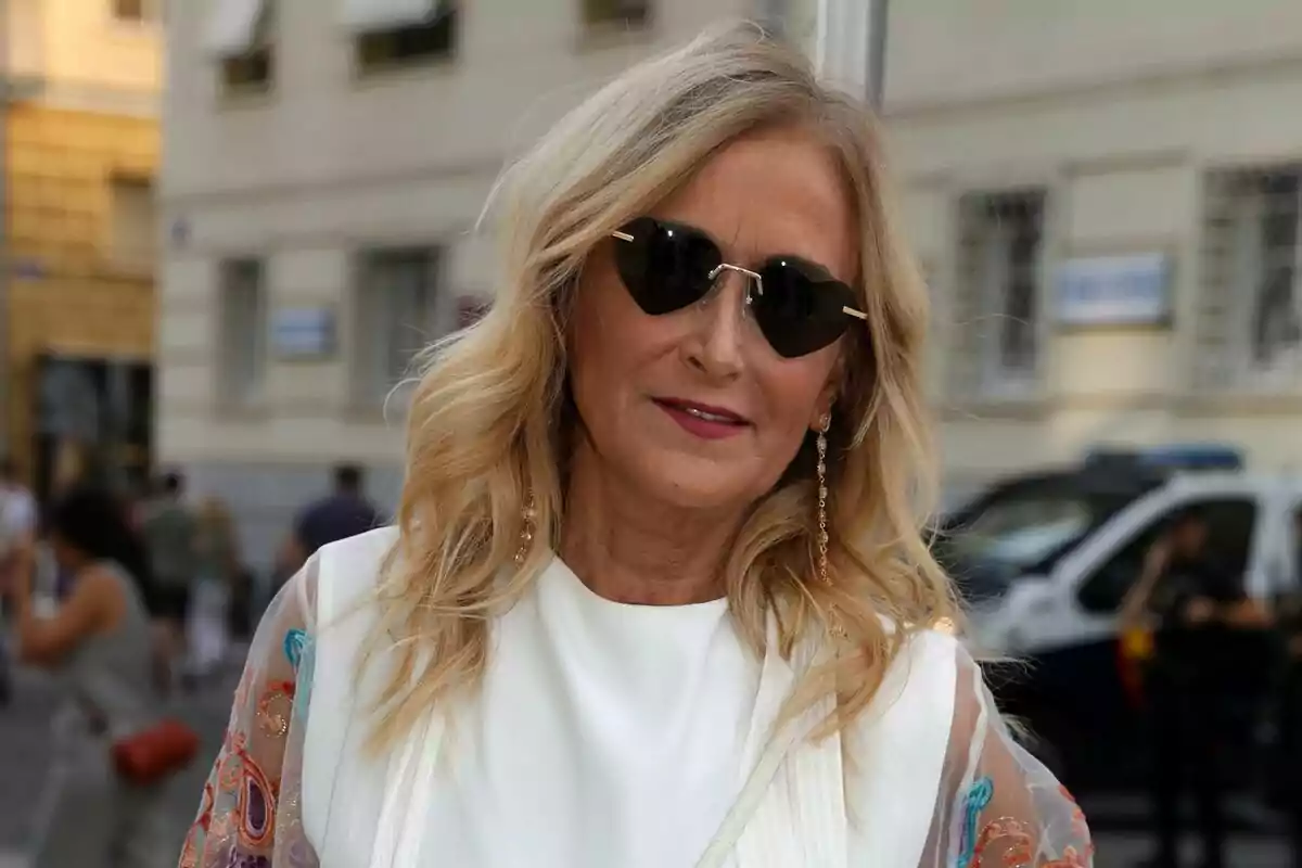 Cristina Cifuentes con gafas de sol en forma de corazón y vestido blanco posando al aire libre en una ciudad. Cristina Cifuentes con gafas de sol en forma de corazón y vestido blanco posando al aire libre en una ciudad.