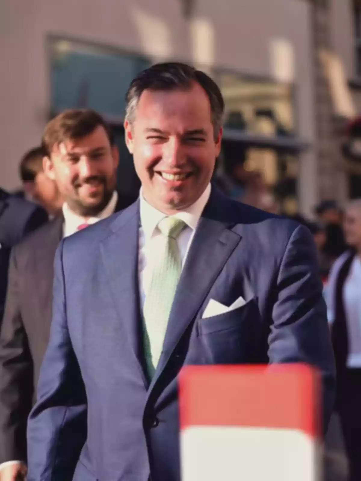 Smiling man in a blue suit and light green tie walking outdoors at a formal event Smiling man in a blue suit and light green tie walking outdoors at a formal event