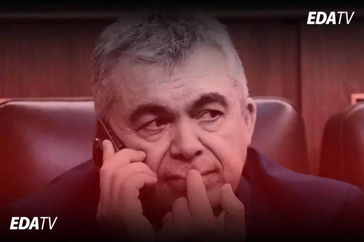 Hombre de cabello canoso sentado en una silla hablando por teléfono con expresión seria y pensativa