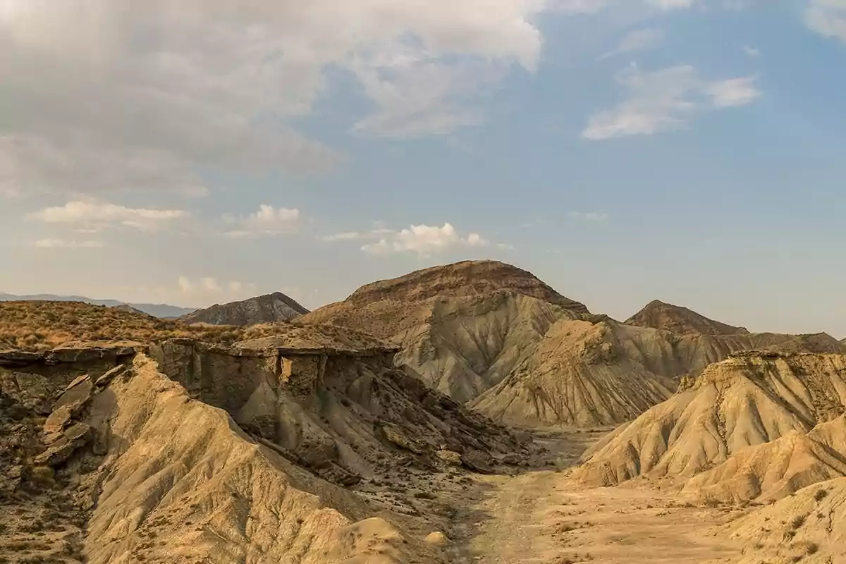 Paisaje árido con colinas rocosas y cielo parcialmente nublado