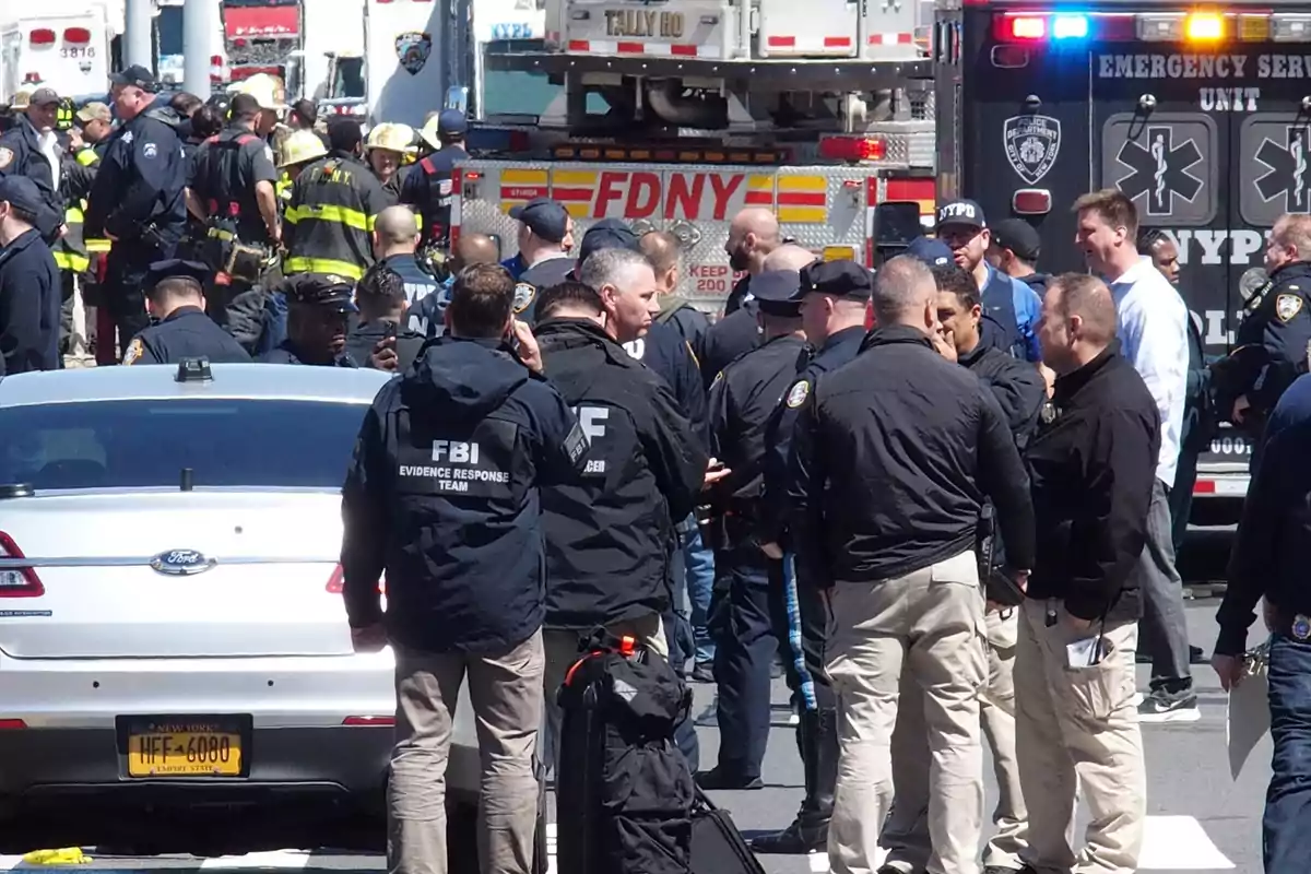 Un grupo de agentes del FBI, policías y bomberos se encuentran reunidos en una calle junto a vehículos oficiales y una ambulancia en una escena de emergencia en Nueva York Un grupo de agentes del FBI, policías y bomberos se encuentran reunidos en una calle junto a vehículos oficiales y una ambulancia en una escena de emergencia en Nueva York
