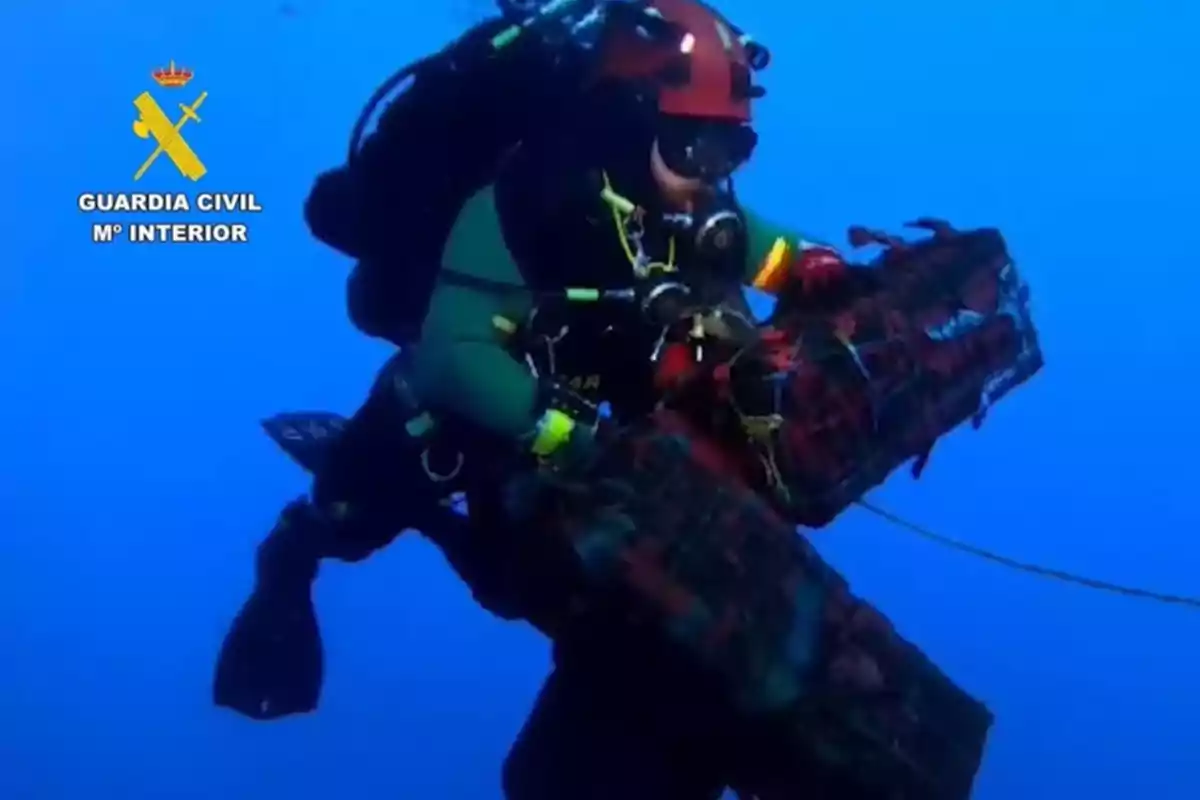 Buzo de la Guardia Civil bajo el agua sosteniendo un paquete grande envuelto con cuerdas Buzo de la Guardia Civil bajo el agua sosteniendo un paquete grande envuelto con cuerdas