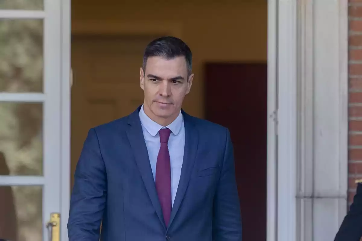 Hombre con traje azul y corbata roja saliendo por una puerta Hombre con traje azul y corbata roja saliendo por una puerta